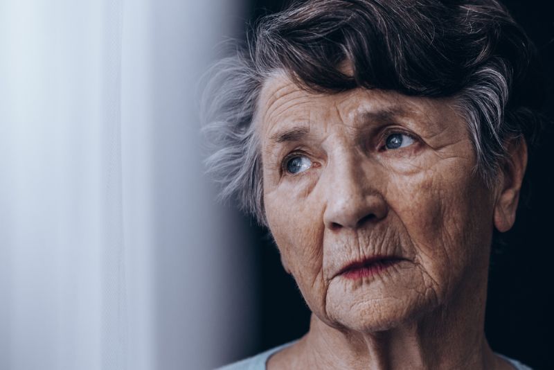 Confused looking older woman standing by window